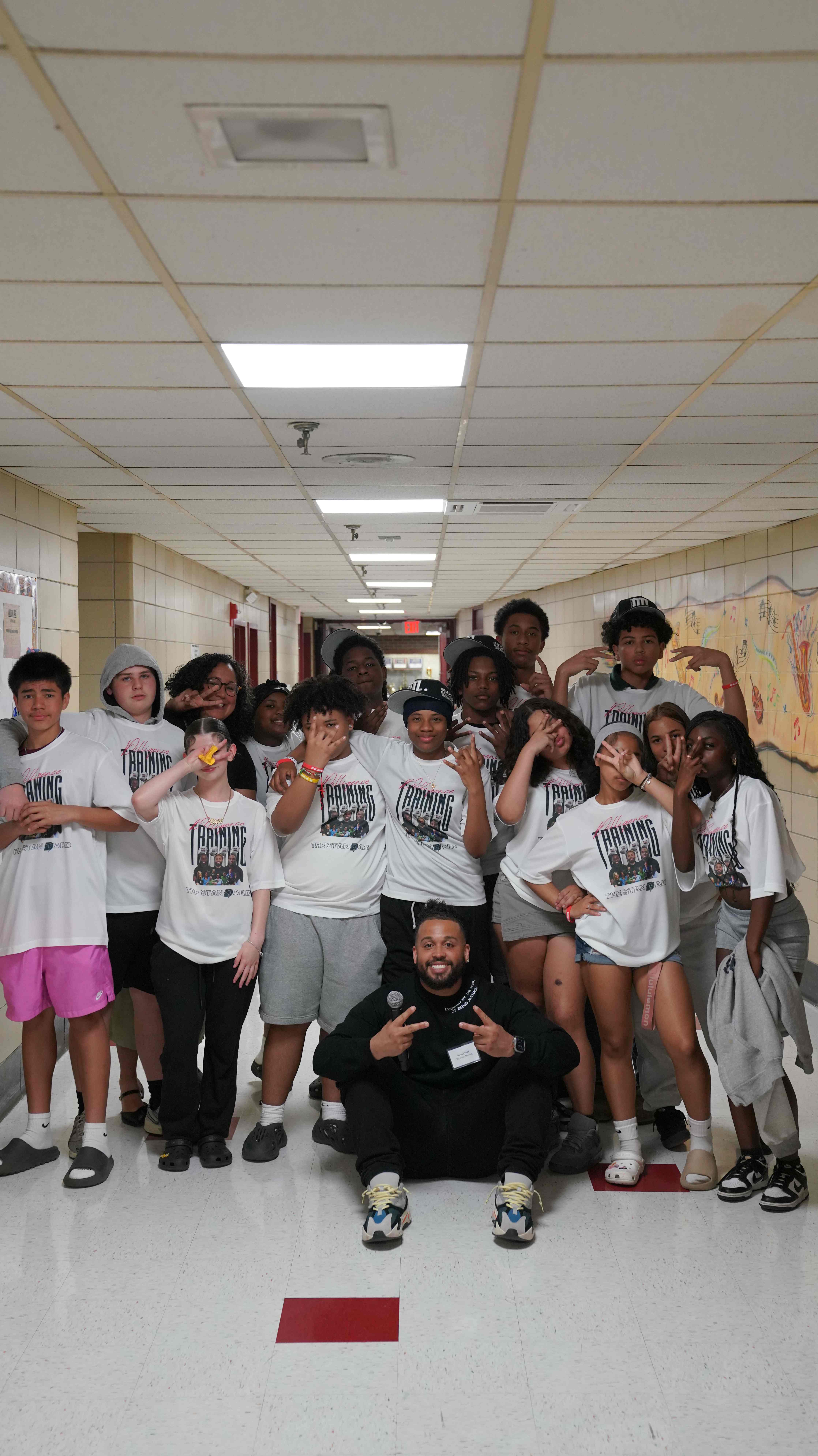 Students in training shirts with mentors in school hallway