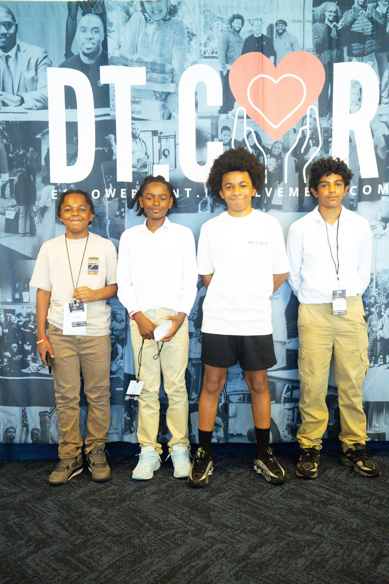Young students posing at the DT Cares backdrop
